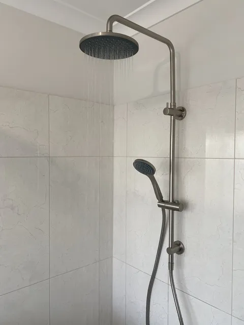 Finished rainhead shower and handheld shower fitting installed in a renovated bathroom
