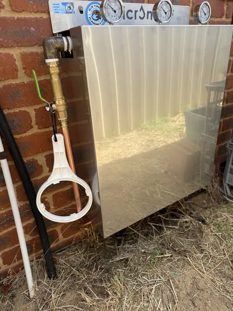 Multi-stage Micron water filtration unit with pressure gauges installed against an exterior brick wall